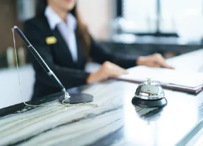 Hotel Associate at the front desk with a bell.